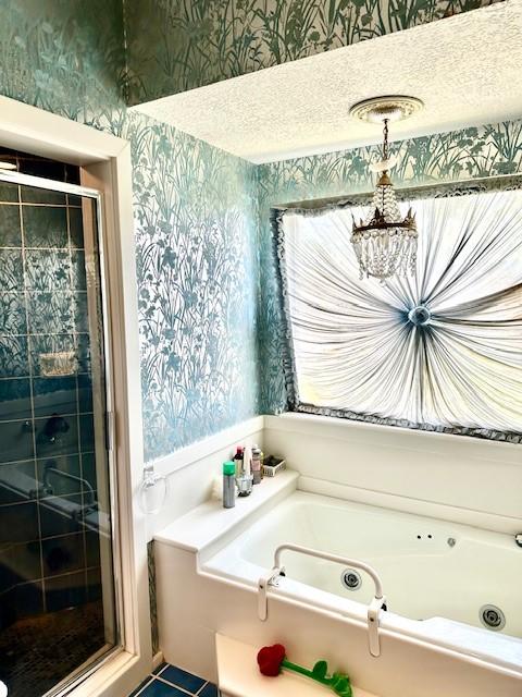 bathroom with a bath, a notable chandelier, a stall shower, and wallpapered walls