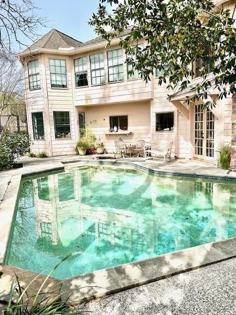 rear view of house with a patio, french doors, and an outdoor pool