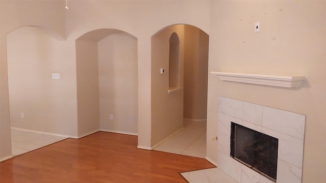 unfurnished living room featuring baseboards, wood finished floors, and a tile fireplace