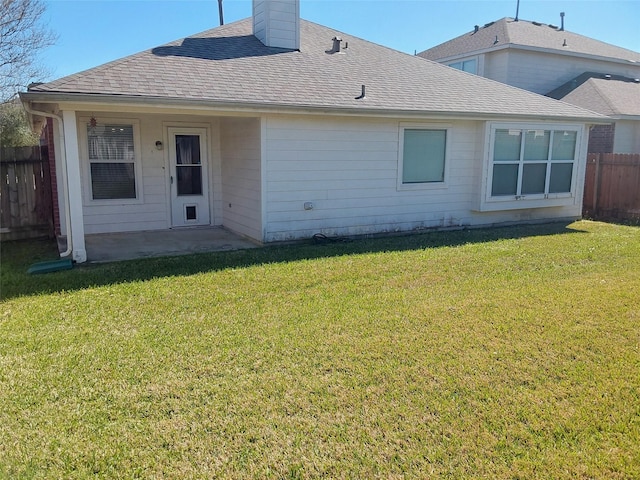 back of property with a shingled roof, fence, a lawn, a chimney, and a patio area