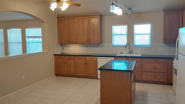 kitchen with a sink, a center island, white appliances, arched walkways, and ceiling fan