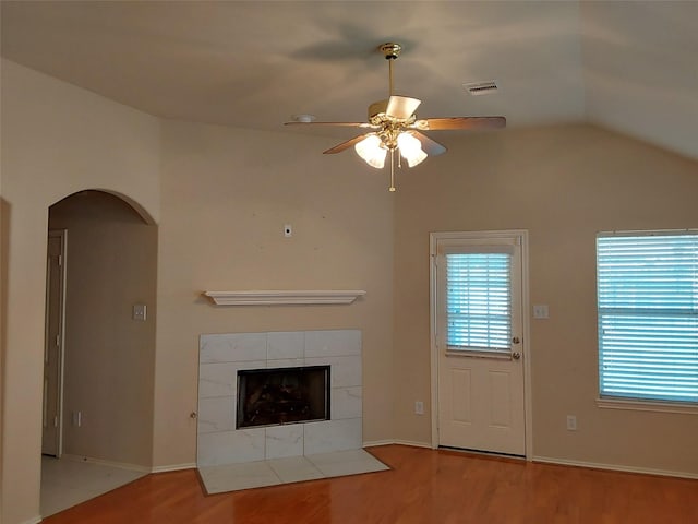 unfurnished living room with visible vents, ceiling fan, vaulted ceiling, wood finished floors, and arched walkways