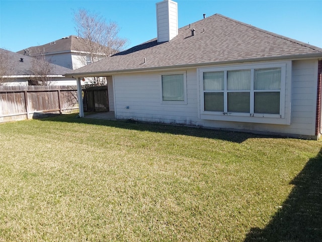 back of house with a chimney, a lawn, fence, and a shingled roof