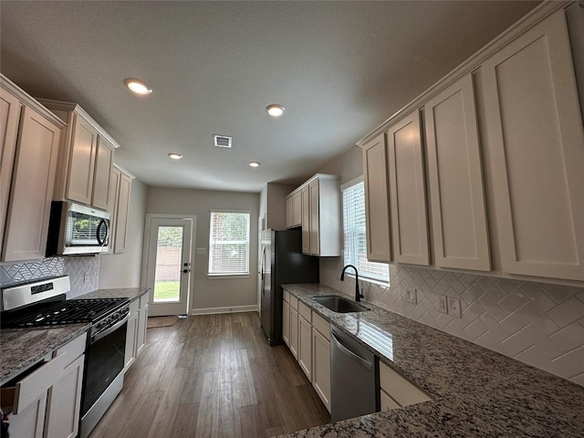 kitchen featuring light stone countertops, visible vents, appliances with stainless steel finishes, and a sink