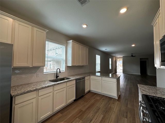 kitchen with dark wood-type flooring, open floor plan, a peninsula, stainless steel appliances, and a sink