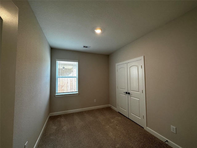 unfurnished bedroom featuring visible vents, baseboards, a closet, and carpet flooring