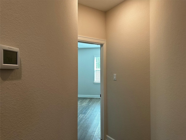 corridor with wood finished floors and a textured wall