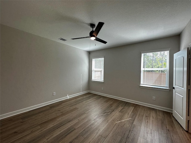 spare room with visible vents, a textured ceiling, baseboards, ceiling fan, and dark wood-style flooring