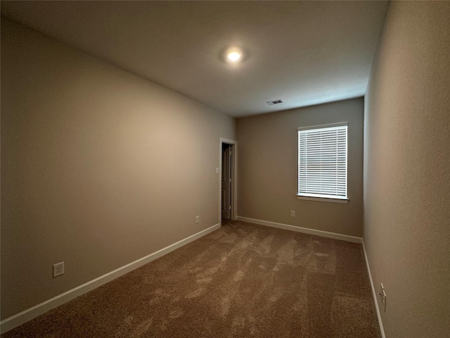 carpeted empty room featuring baseboards and visible vents