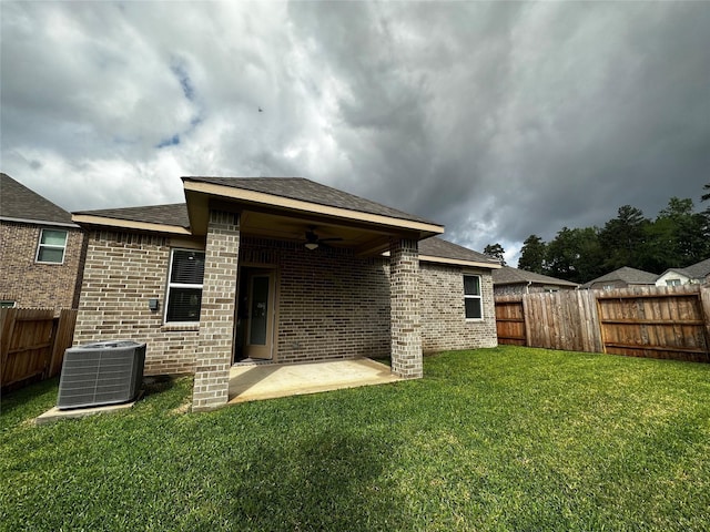 back of house featuring a ceiling fan, a yard, a fenced backyard, central air condition unit, and brick siding