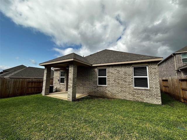 rear view of house featuring a lawn, a fenced backyard, cooling unit, brick siding, and a patio area