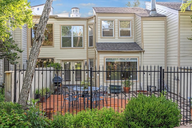 back of property with a patio area, fence, and a shingled roof