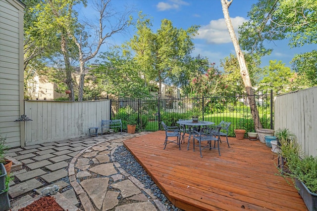 wooden terrace featuring outdoor dining space and a fenced backyard