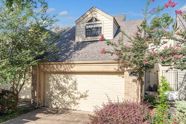 view of front of home with a garage, brick siding, roof with shingles, and concrete driveway