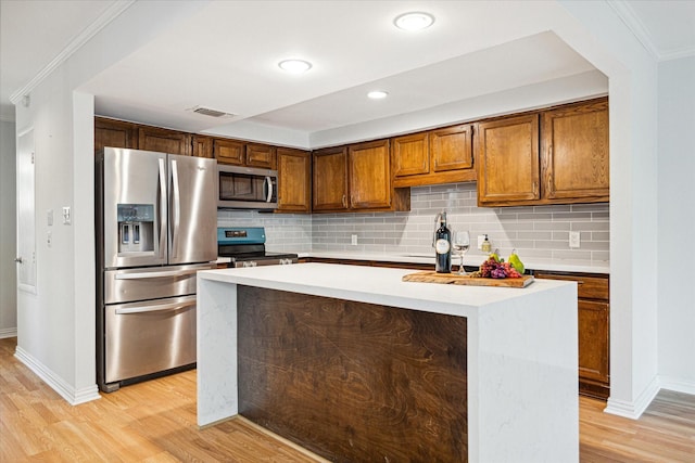 kitchen featuring light wood finished floors, visible vents, a kitchen island, light countertops, and stainless steel appliances