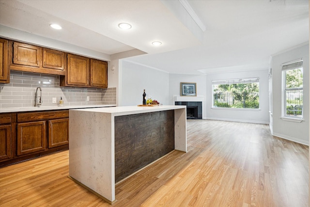 kitchen featuring brown cabinetry, decorative backsplash, light countertops, and a sink