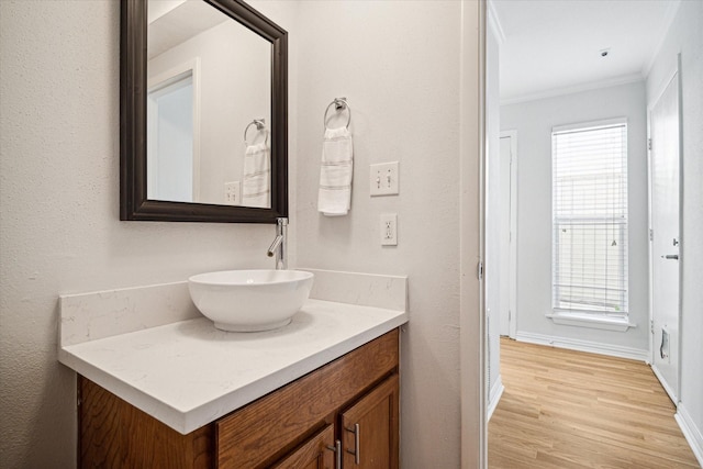 bathroom with vanity, wood finished floors, baseboards, and ornamental molding