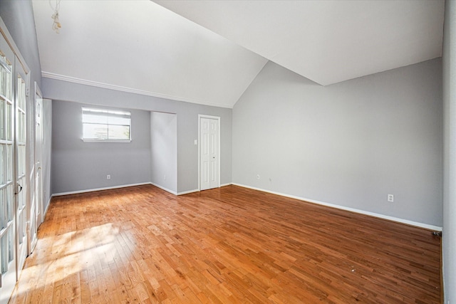 unfurnished bedroom featuring baseboards, lofted ceiling, and light wood-style flooring