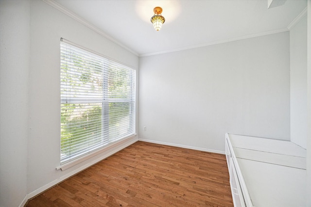 empty room with light wood-type flooring, baseboards, and crown molding