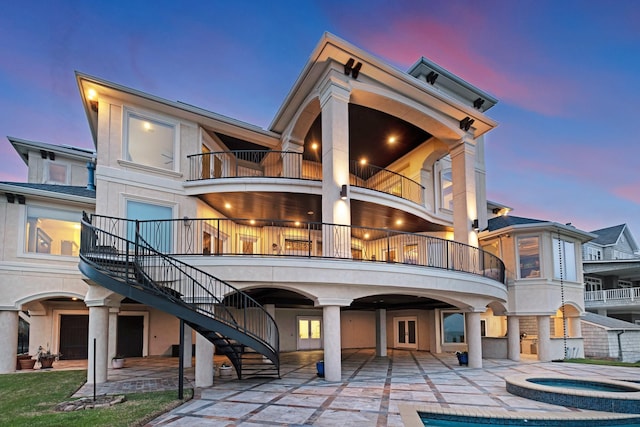 2220 Todville Rd, Seabrook, TX 77586 - back of house at dusk with a patio, stairway, a pool with connected hot tub, and stucco siding
