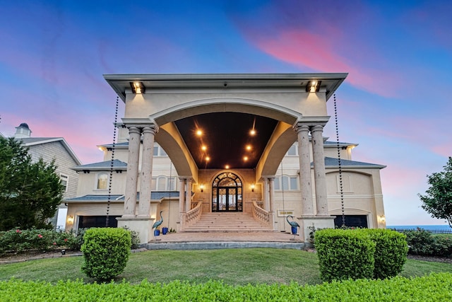2220 Todville Rd, Seabrook, TX 77586 - exterior entry at dusk with a lawn, a garage, and stucco siding