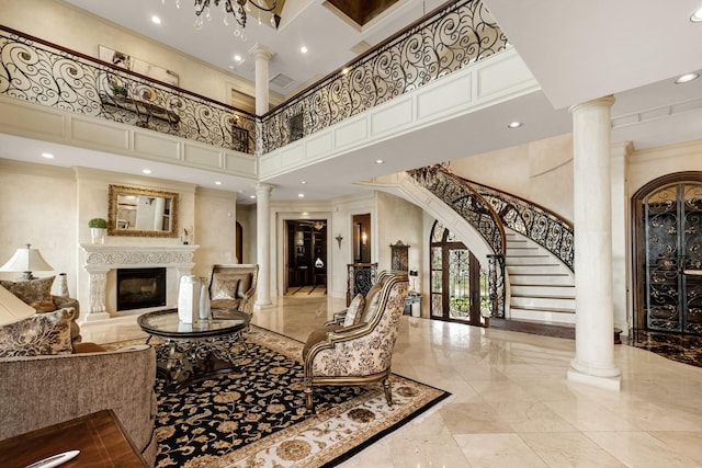 2220 Todville Rd, Seabrook, TX 77586 - living area featuring a towering ceiling, ornate columns, a glass covered fireplace, marble tiled flooring, and stairway