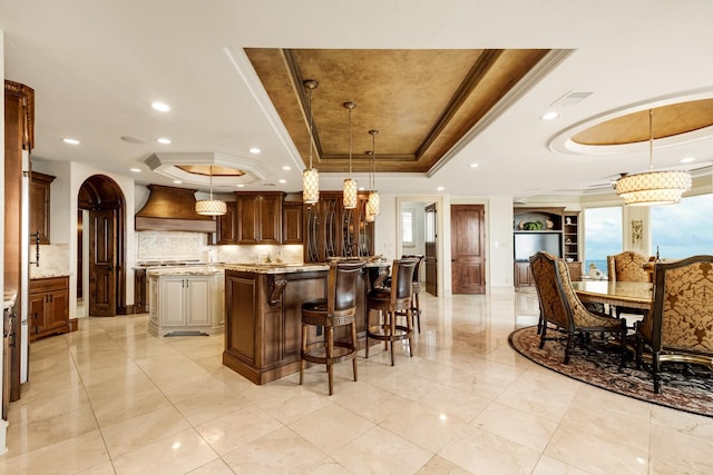 2220 Todville Rd, Seabrook, TX 77586 - kitchen featuring tasteful backsplash, crown molding, a tray ceiling, custom range hood, and a large island
