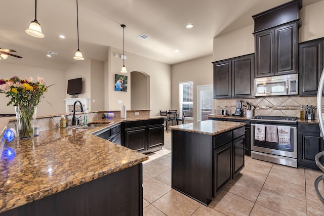 kitchen featuring visible vents, backsplash, appliances with stainless steel finishes, a large island, and a sink