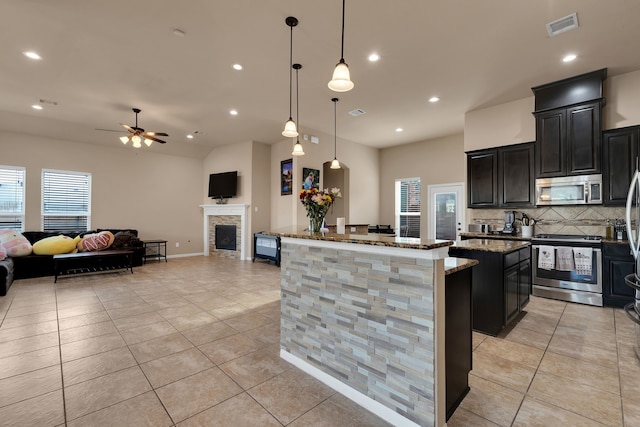 kitchen with dark stone countertops, visible vents, a kitchen island, stainless steel appliances, and dark cabinets