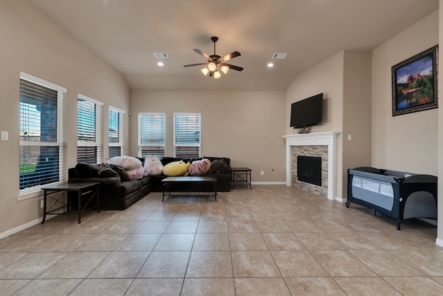 living room featuring baseboards, ceiling fan, lofted ceiling, light tile patterned floors, and a stone fireplace