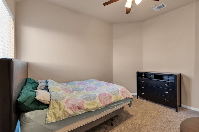 bedroom featuring ceiling fan, multiple windows, visible vents, and light carpet