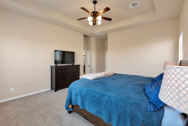 bedroom with light carpet, visible vents, baseboards, and a tray ceiling