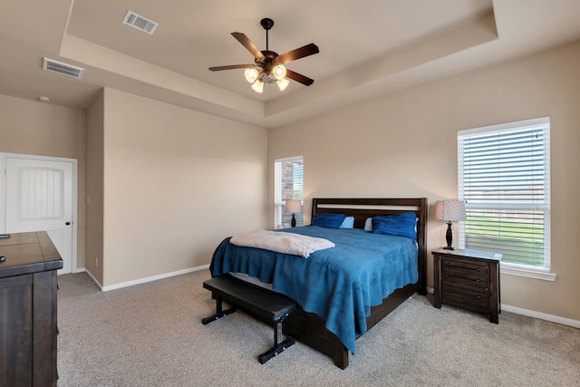 bedroom featuring light carpet, visible vents, and a raised ceiling