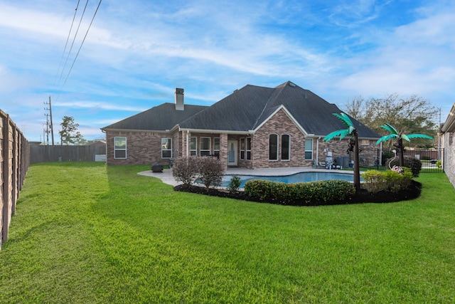 back of house featuring a patio area, a yard, brick siding, and a fenced backyard