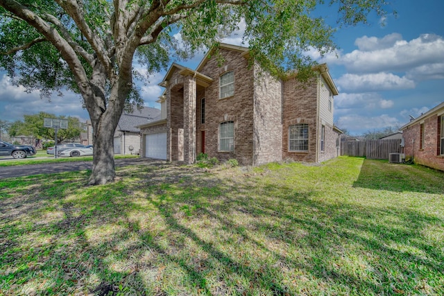 traditional home with driveway, fence, a front yard, an attached garage, and brick siding