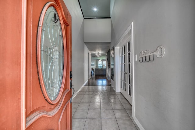 foyer entrance with light tile patterned flooring, french doors, and baseboards