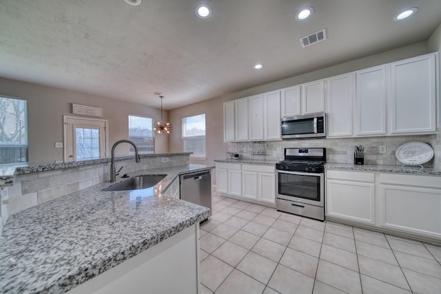 kitchen featuring light tile patterned floors, a sink, stainless steel appliances, white cabinetry, and tasteful backsplash