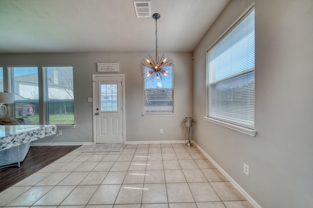 entrance foyer with an inviting chandelier, baseboards, visible vents, and a wealth of natural light