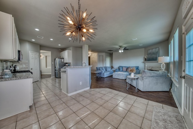 living room with visible vents, light tile patterned floors, ceiling fan with notable chandelier, a fireplace, and recessed lighting