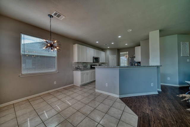 kitchen featuring fridge, visible vents, white cabinetry, stainless steel microwave, and a notable chandelier