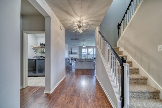 entryway featuring wood finished floors, baseboards, visible vents, washing machine and clothes dryer, and stairs