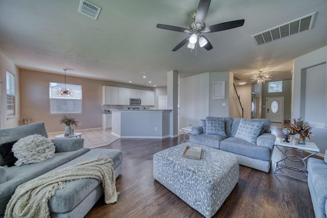 living room featuring visible vents, wood finished floors, baseboards, and ceiling fan