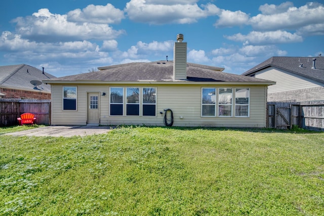 back of property featuring a fenced backyard, a lawn, a chimney, and a patio