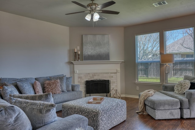 living area with visible vents, wood finished floors, a fireplace, baseboards, and ceiling fan