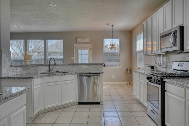 kitchen featuring a sink, stainless steel appliances, backsplash, and white cabinetry