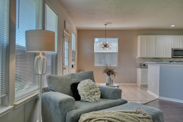 living area with a chandelier, visible vents, and baseboards