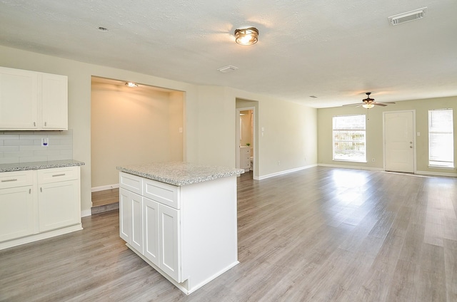 5343 Linda Ln, Katy, TX 77493 - kitchen with visible vents, a ceiling fan, a kitchen island, light wood-style floors, and decorative backsplash