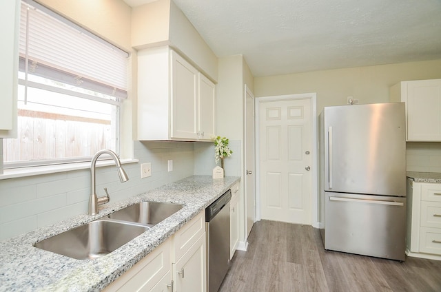 5343 Linda Ln, Katy, TX 77493 - kitchen with tasteful backsplash, appliances with stainless steel finishes, light wood-style floors, white cabinets, and a sink