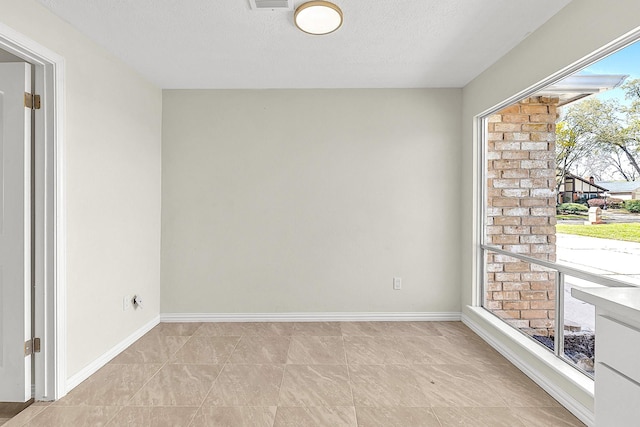 unfurnished room with a textured ceiling and baseboards