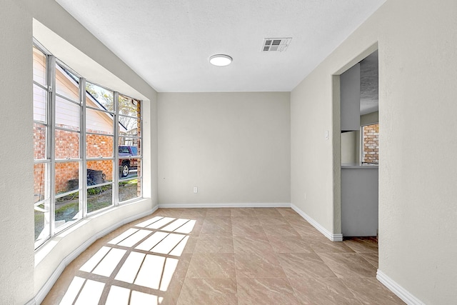 empty room with visible vents, baseboards, and a textured ceiling